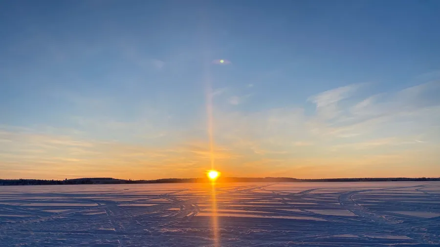 Sol invernal bajo sobre el lago nevado