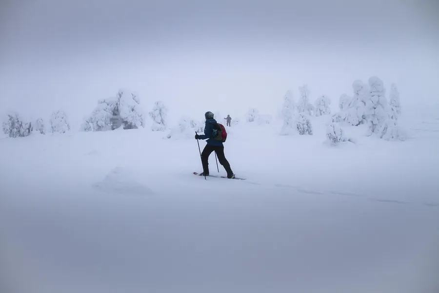 Persona caminando por un paisaje nevado con niebla