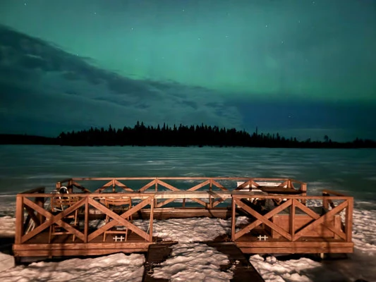 Nordlichter über einem See mit Holzgeländer im Vordergrund