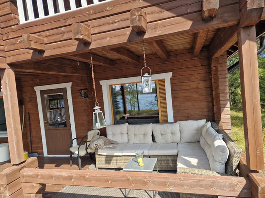 Überdachte Terrasse am Blockhaus mit Sofa und Tisch