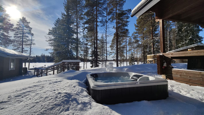 Whirlpool auf der verschneiten Terrasse neben dem Holzhaus