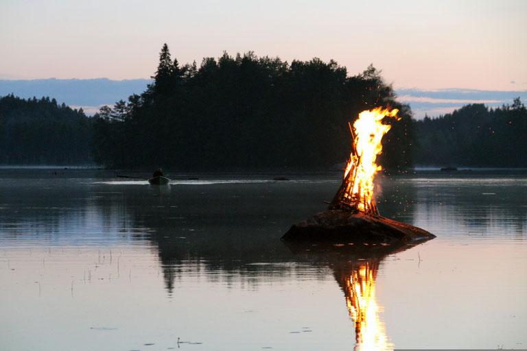 Brennendes Feuer auf einer kleinen Plattform im See bei Dämmerung