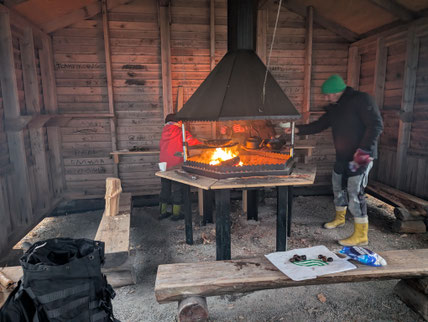 Feuer in einer zentralen Feuerstelle mit Rauchabzug in einer Holzhütte