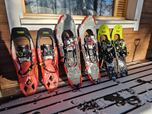 Schneeschuhe stehen nebeneinander an der Holzwand auf der Terrasse