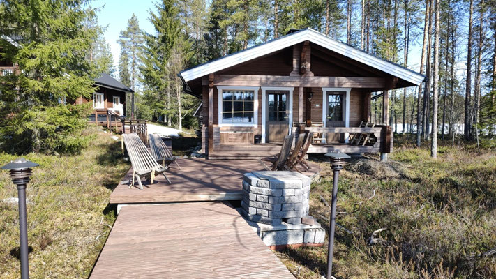Holzsteg führt zum kleinen Haus zwischen den Bäumen