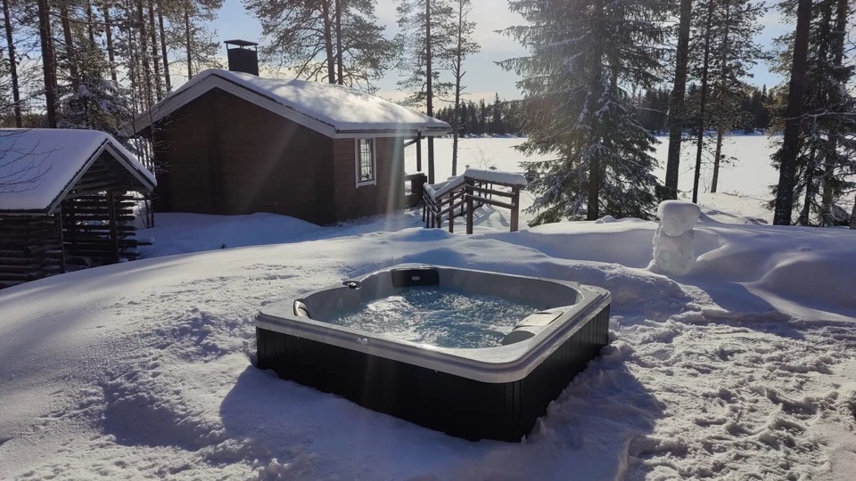 Whirlpool im Schnee mit Blick zum Saunahaus und See