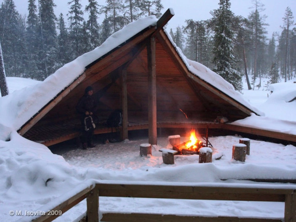 Holzunterstand mit Feuerstelle im verschneiten Wald