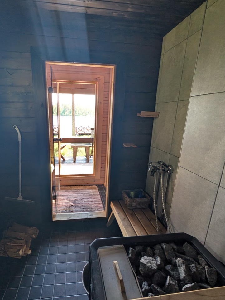 Saunaofen mit Steinen und Blick durch die Tür zum Kaminzimmer